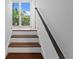 Staircase with hardwood steps, white risers, and a unique twisted metal handrail leading to a balcony at 1122 Shipwatch Cir, Tampa, FL 33602
