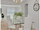 Elegant dining area with a glass table, white chairs, modern lighting and ample natural light for an inviting space at 11296 115Th St, Largo, FL 33778