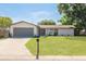 Charming single-story home with a well-manicured lawn, grey trim and a two-car garage on a sunny day at 11296 115Th St, Largo, FL 33778