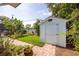 Green backyard featuring a storage shed and lush tropical landscaping and brick trim at 1235 Nelson St, Dunedin, FL 34698