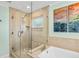 Bathroom boasting a glass-enclosed shower with tiled walls, and tub featuring decorative paintings at 1235 Nelson St, Dunedin, FL 34698