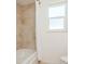 Bathroom with a white shower curtain rod, beige marble-esque shower tiles, and a clear-paned window at 1247 Overcash Dr, Dunedin, FL 34698