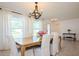 Dining room with a wooden table and white chairs illuminated by a stylish chandelier and natural light at 1247 Overcash Dr, Dunedin, FL 34698