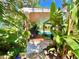 View from backyard toward a covered porch, lush landscaping, and outdoor pool at 1330 Belcher Dr, Tarpon Springs, FL 34689