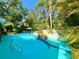 Backyard featuring a pool, patio with colorful seating, and lush landscaping, creating a private retreat at 1330 Belcher Dr, Tarpon Springs, FL 34689