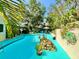 Backyard pool features vibrant blue tiling, custom rock feature, lush landscaping, and outdoor seating area for entertaining at 1330 Belcher Dr, Tarpon Springs, FL 34689