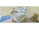 Bright bedroom features a comfortable bed, neutral carpet, and view to exterior with large sunny window at 14130 Rosemary Ln # 4115, Largo, FL 33774