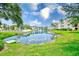 Picturesque pond view surrounded by lush greenery and community buildings, creating a tranquil atmosphere at 14130 Rosemary Ln # 4115, Largo, FL 33774