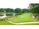 Scenic view of the lake with a grassy green shoreline and walking path, surrounded by lush trees and greenery at 14667 Pine Glen Crk # 14667, Lutz, FL 33559