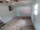 Vacant Living Room with multiple windows, peeling paint, baseboards, and dirty floors in need of repair at 1785 42Nd S St, St Petersburg, FL 33711