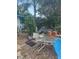 Backyard patio area showing overgrown foliage and neglected outdoor furniture at 1831 Pasadena Dr, Dunedin, FL 34698