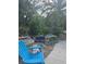 Backyard patio area showing overgrown vegetation and neglected outdoor furniture at 1831 Pasadena Dr, Dunedin, FL 34698