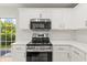 Modern kitchen with stainless steel appliances, white cabinetry and view to backyard at 2032 Sunset Meadow Dr, Clearwater, FL 33763