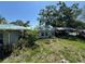 The side and back exterior shows an attached carport with an overgrown yard and weathered siding at 2402 E 148Th Ave, Lutz, FL 33549