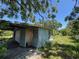 Dilapidated garage structure featuring peeling paint, rotted wood, and overgrown foliage at 2402 E 148Th Ave, Lutz, FL 33549