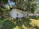 A white outbuilding is overtaken by vegetation and shaded by trees at 2402 E 148Th Ave, Lutz, FL 33549
