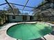 A kidney-shaped pool enclosed with a screen enclosure under a blue sky at 2402 E 148Th Ave, Lutz, FL 33549