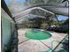 An in-ground pool is surrounded by concrete patio and enclosed with screening with a side ladder at 2402 E 148Th Ave, Lutz, FL 33549