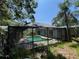 A partially obstructed in-ground screened pool is surrounded by lush foliage and shade at 2402 E 148Th Ave, Lutz, FL 33549