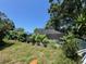 View of a screened pool surrounded by overgrown greenery, adjacent to the side of the house at 2402 E 148Th Ave, Lutz, FL 33549