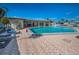 Large community in-ground pool with lounge chairs, tables, and chairs. Brick surrounding at 250 Rosery Nw Rd # 218, Largo, FL 33770