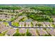 An aerial view shows a lush, green neighborhood with pond and landscaping, surrounded by trees at 31108 Whitlock Dr, Wesley Chapel, FL 33543
