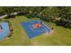 Aerial view of a well-maintained basketball court with a new surface, enclosed by a tall green fence, next to a playground at 3201 Pine Top Dr, Valrico, FL 33594