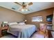 Bedroom features wooden floors, a ceiling fan, and a window offering natural light, and two bedside lamps at 34389 Orchid Pkwy, Ridge Manor, FL 33523