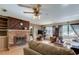 A cozy living room featuring a classic brick fireplace, wood floors, and natural light at 34389 Orchid Pkwy, Ridge Manor, FL 33523