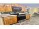 Well-lit kitchen featuring black appliances, wood cabinets, and durable stone-look flooring at 406 2Nd Sw St, Ruskin, FL 33570