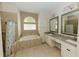 Bright bathroom featuring double sinks, soaking tub, decorative mirrors and neutral tile at 4657 Parkway Blvd, Land O Lakes, FL 34639