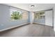 A bedroom with light blue walls, a ceiling fan, gray floors and views of the outside through the windows at 5027 Overton Dr, New Port Richey, FL 34652