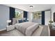 Staged bedroom with ceiling fan, large windows and grey wood floors at 5027 Overton Dr, New Port Richey, FL 34652