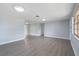 Open floor plan with gray wood-look flooring, white trim, and natural light from the window at 5027 Overton Dr, New Port Richey, FL 34652
