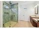 Bathroom featuring a stone-tiled shower with glass door, pebble floor, and wooden vanity at 511 Roanoke St, Dunedin, FL 34698