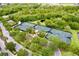 Aerial view of community tennis courts with trees, bushes, landscaping, and a pond at 5225 Brighton Shore Dr, Apollo Beach, FL 33572