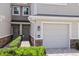 Close up of a townhome exterior with a one-car garage, brick paved drive and tropical shrubs at 5496 Riverwalk Preserve Dr, New Port Richey, FL 34653