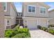 Townhomes with garage, double doors, brick paved drive, tropical shrubs, and street lamp at 5496 Riverwalk Preserve Dr, New Port Richey, FL 34653