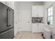 Clean and well-organized pantry area with white cabinets, granite countertops, and stainless steel refrigerator at 5496 Riverwalk Preserve Dr, New Port Richey, FL 34653