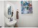 Chic powder room with pedestal sink, stylish mirror, and decorative artwork at 5496 Riverwalk Preserve Dr, New Port Richey, FL 34653