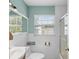 Bathroom with white tile, updated fixtures, glass door shower, and a bright window at 6183 5Th S Ave, St Petersburg, FL 33707