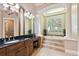 Luxurious bathroom features a soaking tub, elegant vanities, a pillar, and plenty of natural light at 704 Berrocales De Avila, Tampa, FL 33613