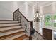 Elegant staircase with wood steps, wrought iron railing and chandelier, leading to the upper level at 704 Berrocales De Avila, Tampa, FL 33613