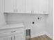 Functional laundry room with white cabinets, stone countertops, and sleek hardware at 718 Desert Hills Way, Sun City Center, FL 33573