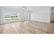 Bright, airy living room with wood-look flooring, white walls, and large windows offering neighborhood views at 718 Desert Hills Way, Sun City Center, FL 33573