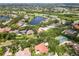 Picturesque aerial view of a neighborhood with a golf course, lake, tennis court, and beautifully landscaped properties at 9075 Waterash N Ln, Pinellas Park, FL 33782