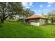 Spacious backyard with lush green grass, mature trees, and a screened-in pool at 9075 Waterash N Ln, Pinellas Park, FL 33782
