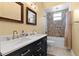 Dual sink vanity in a well-lit bathroom with decorative tile accent in shower at 9075 Waterash N Ln, Pinellas Park, FL 33782
