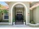 Elegant double front doors framed by an arched entryway, complemented by potted plants and sconce lighting at 9075 Waterash N Ln, Pinellas Park, FL 33782