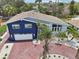 Aerial view of a two-story home with a two-car garage, brick driveway, and lush, tropical landscaping at 931 Gulf Blvd, Belleair Beach, FL 33786